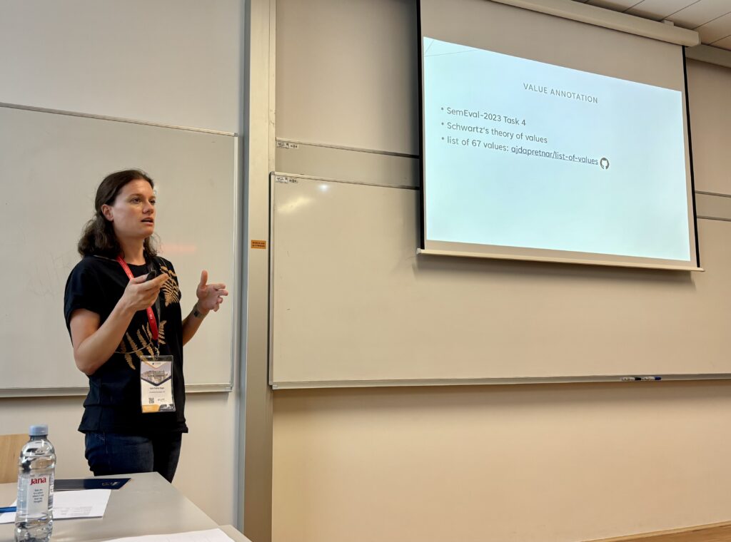 Woman standing in the classroom presenting about her research on large language models and values.